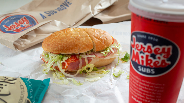A Jersey Mike's sandwich with a branded Jersey Mike's bag behind it, and a Jersey Mike's branded drink in front of it