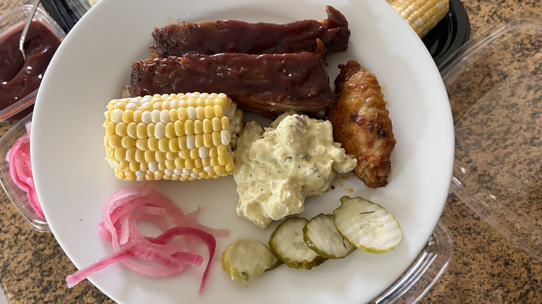 Barbecue ribs, corn, and potato salad on a plate