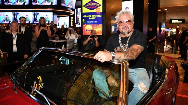 Guy Fieri posing with his red car from 