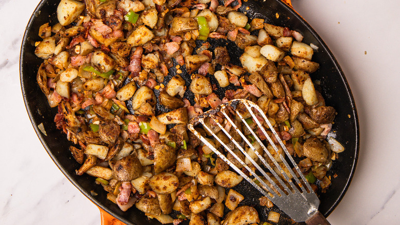 mixing spiced cowboy-style potatoes in pan