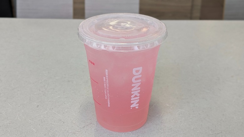 A Strawberry Sparkling Limeade from Dunkin' on a grey table