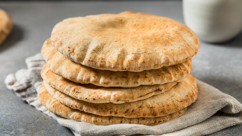 Stack of Greek pita breads on a folded gray linen cloth