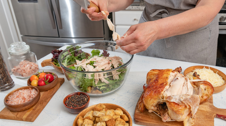 Person making a chicken salad with a rotisserie style cooked chicken