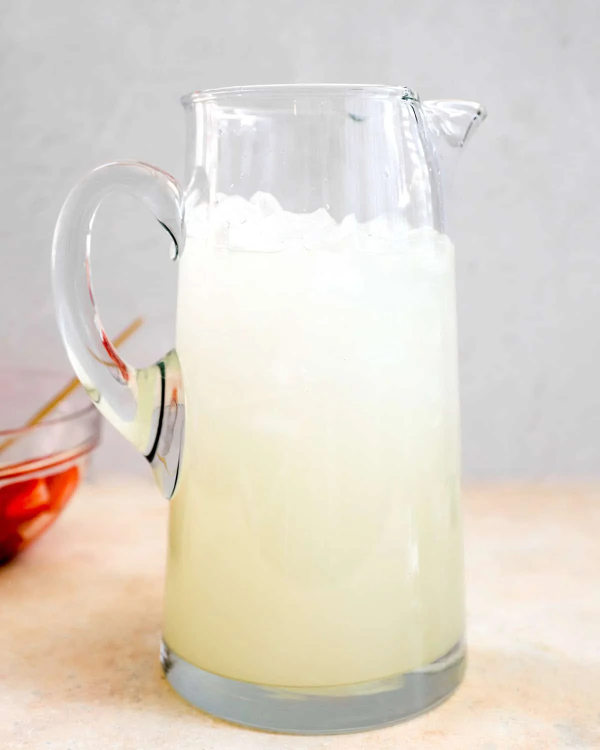 Glass pitcher filled with fresh lemonade and ice before the strawberries are added
