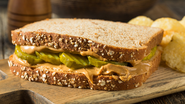 A peanut butter and pickle sandwich, accompanied by potato chips