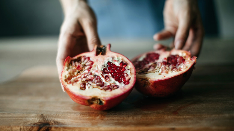Person holding two halves of pomegranate