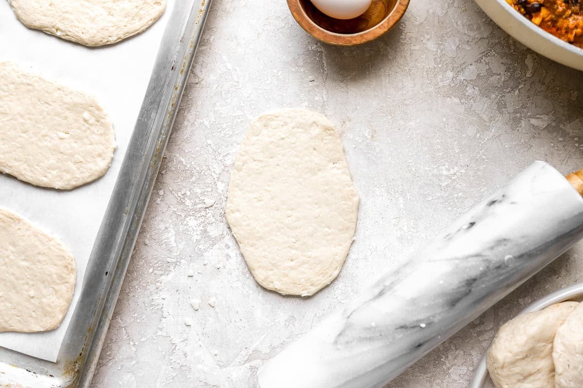 Biscuit dough rolled into a rectangle on a parchment-lined baking sheet for taco hot pockets.