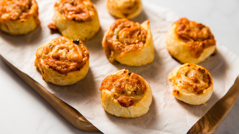 Cheesy pizza pinwheels on parchment-lined wooden board