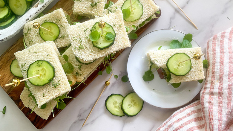 Cucumber tea sandwiches on wooden board and white plate
