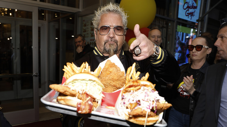 Guy Fieri with sandwiches, tenders and fries from Chicken Guy!