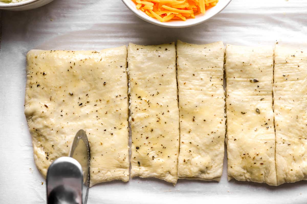 Stuffed cheesy bread dough sliced into individual breadsticks before baking