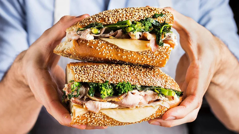 Hands holding Roast Pork and Broccoli Rabe Sandwich