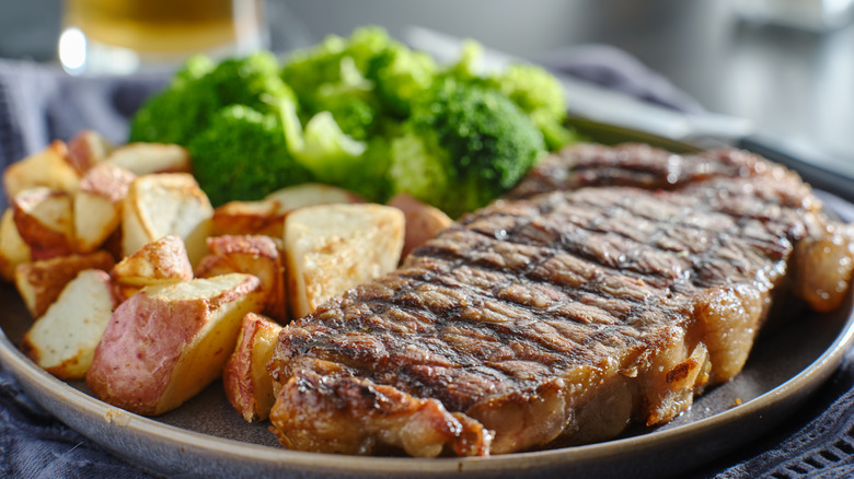 grilled steak with broccoli and roasted potatoes on plate