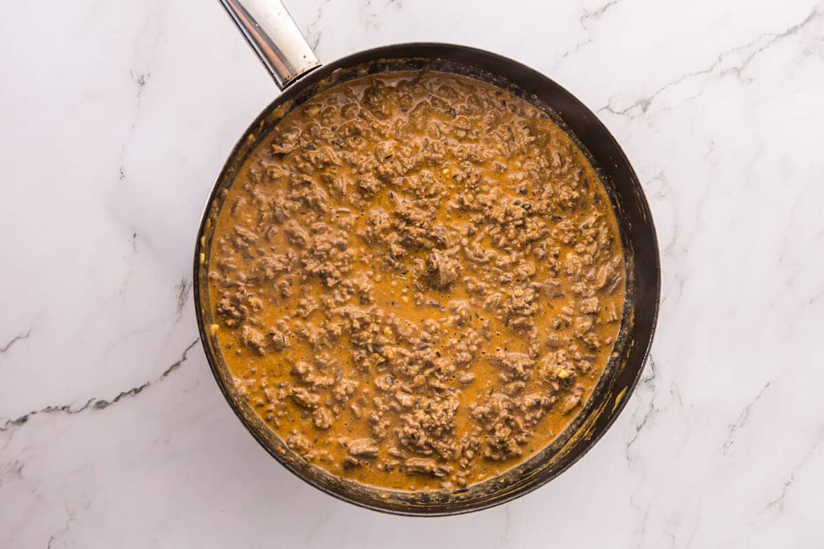 Thickened, creamy beef stroganoff sauce coating ground beef and mushrooms in a skillet
