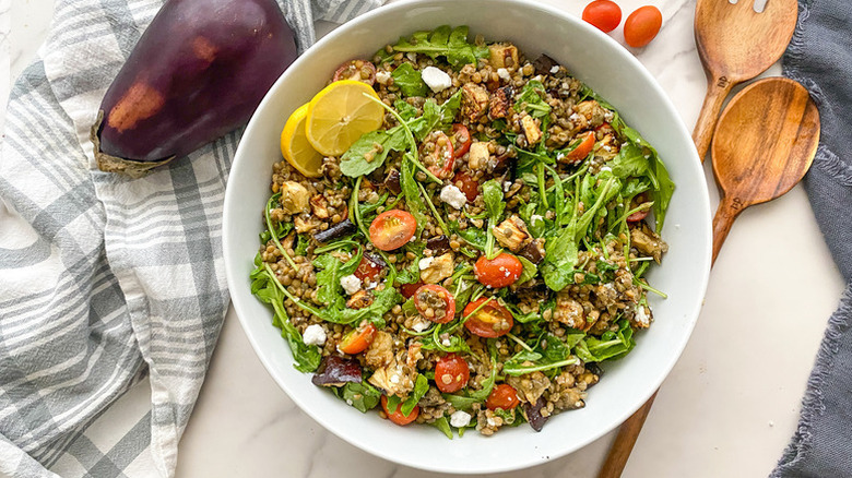 Kale, chickpea, and dukkah salad with pomegranate seeds on white serving plate