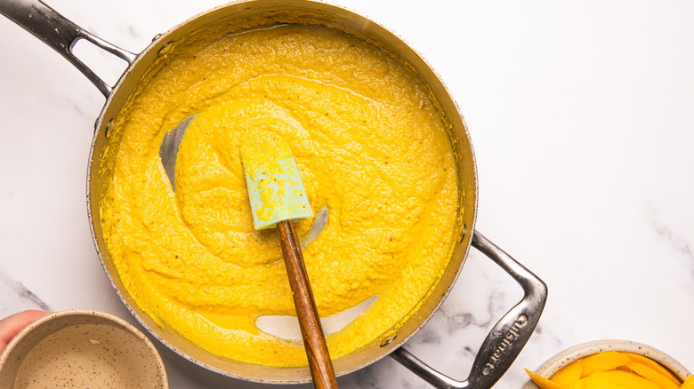 Mixing coconut curry sauce in large pan.