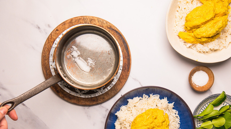 Holding saucepan with coconut oil.