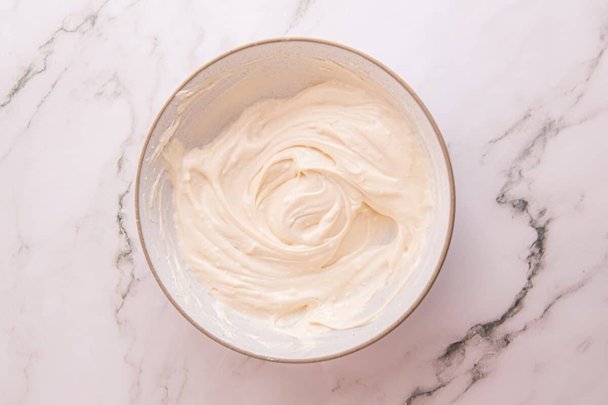 Smooth sweetened cream cheese mixture swirled in a bowl, ready to be piped into cheesecake bites
