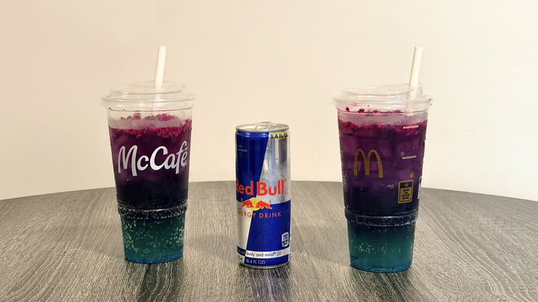 A can of Red Bull between a regular and zero-sugar McDonald's Red Bull Dragonberry Energizer
