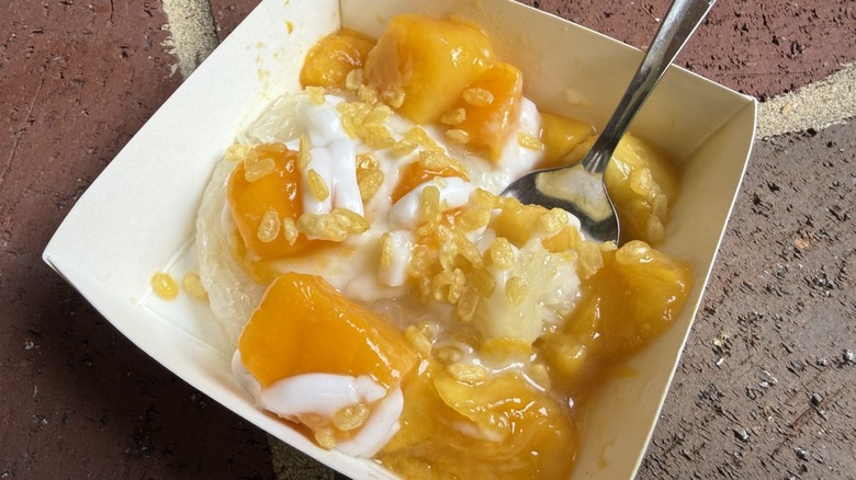 Freshly prepared mango sticky rice inside serving tray with metal spoon