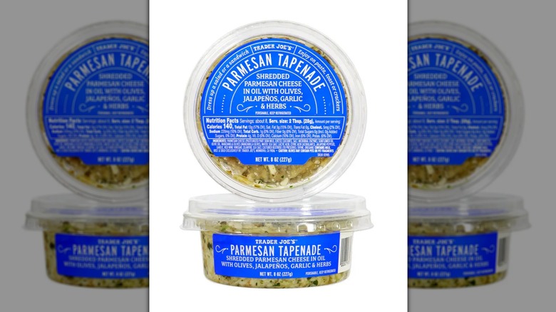 Two tubs of Trader Joe's Parmesan Tapenade stacked on top of one another with top container on white background