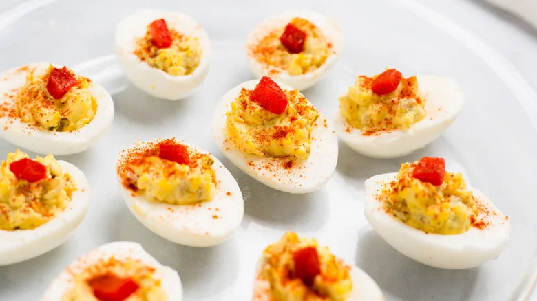 A plate filled with deviled eggs, garnished with pimentos and paprika.