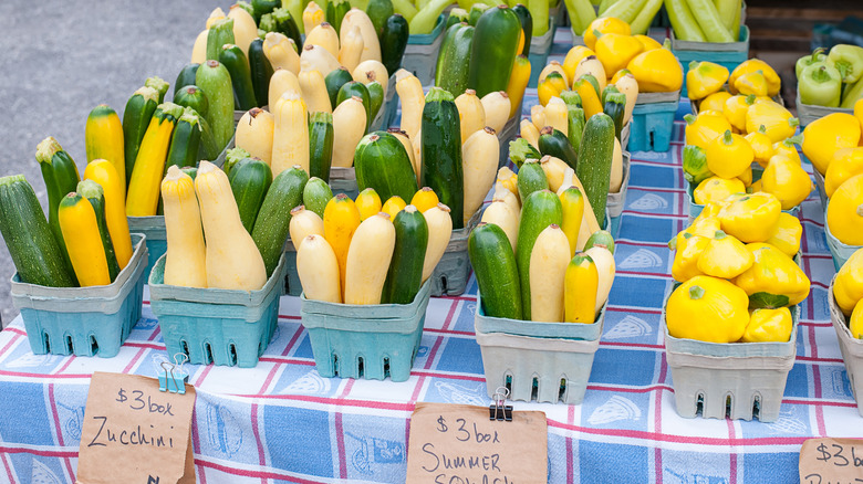 Baskets of different varieties of summer squash for sale at an outdoor market