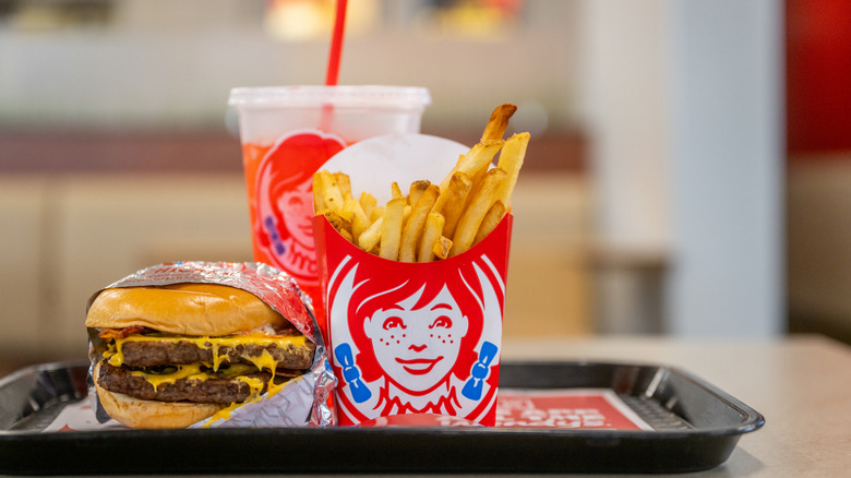 A double cheeseburger, fries, and soda from Wendy's sitting on a plastic tray