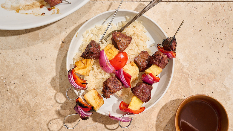beef kabobs on a plate with rice