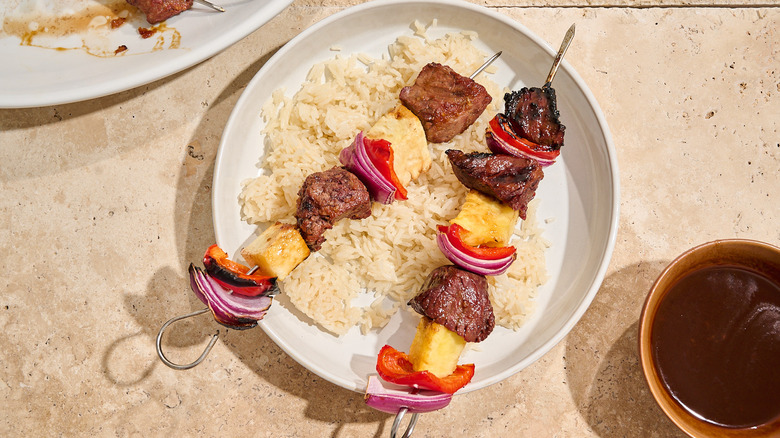 beef kabobs on a plate with rice