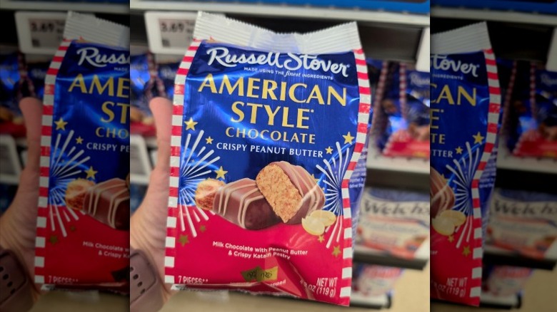 A hand holding a bag of Russell Stover American Style Chocolate candies