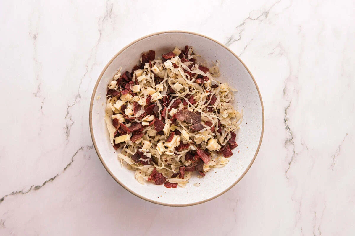 A bowl of crisped corned beef, shredded sauerkraut, and chopped Swiss cheese mixed together for the filling.