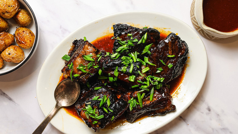 Slow-cooked ribs on a plate, garnished with green onion