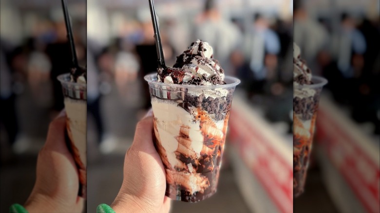 A person's hand holding a cup of Costco's Vanilla Cookie Crunch Sundae from Costco