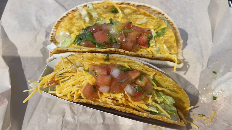A taco sits in a Taco bell branded holder with another taco behind it.