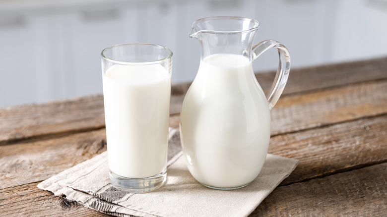A full glass of milk next to a full jar of milk.