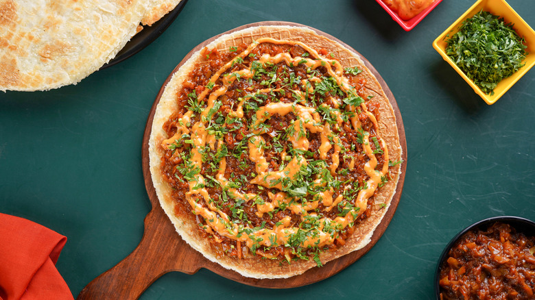 Indian-style dosa pizza on table beside toppings