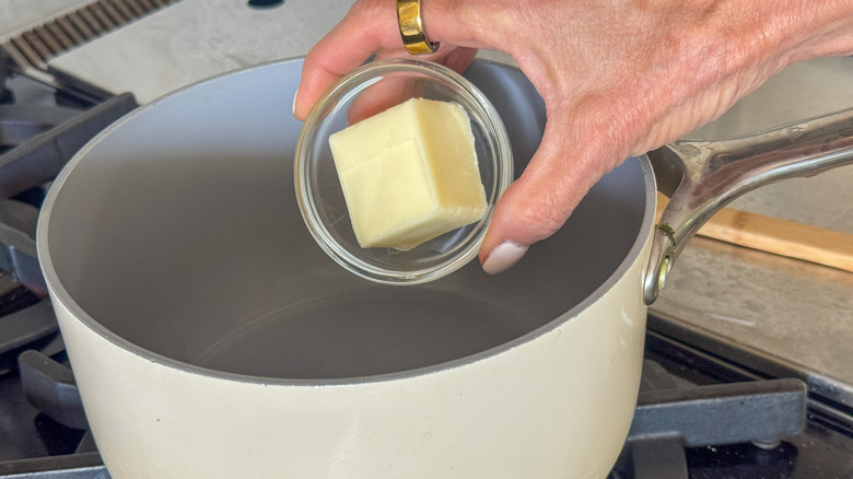 hand adding butter to pot