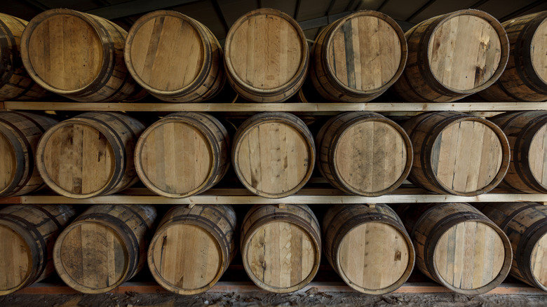 Barrels of aging whiskey on a shelf.