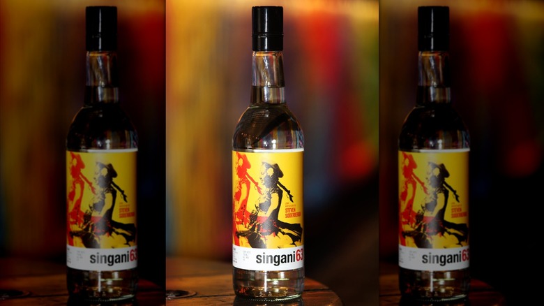 A bottle of Singani 63 with a yellow label against a blurred background.