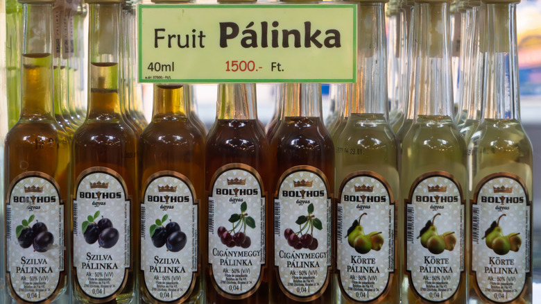 Rows of palinka bottles in various flavors on a market stall.