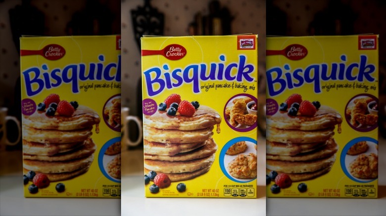 The front of a box of Betty Crocker Bisquick Original Pancake & Baking Mix, with several berries on top of a stack of pancakes visible, as well as some fried food sitting beside a bowl of ketchup