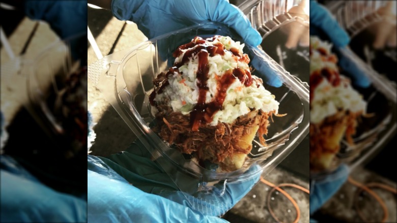 Pulled pork sundae in plastic tray with coleslaw and BBQ sauce