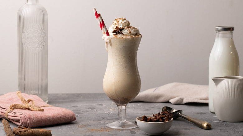 Chai vanilla milkshake in a tall glass with straws and a whipped cream topping
