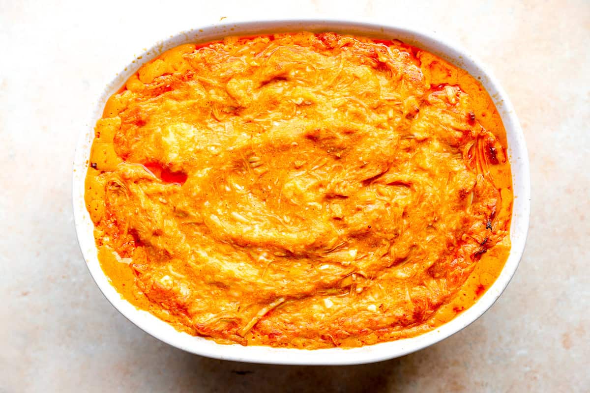 Baked buffalo chicken dip fresh out of the oven, golden and bubbling in a white baking dish.