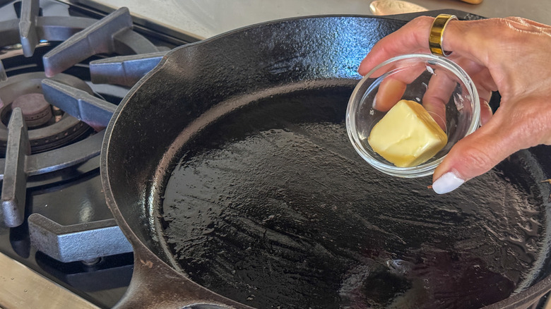 hand adding butter to skillet