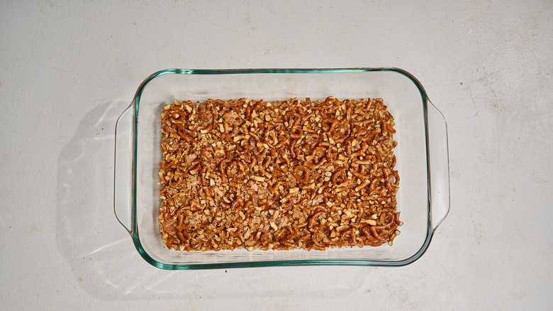 pressing pretzels into the base of a casserole dish