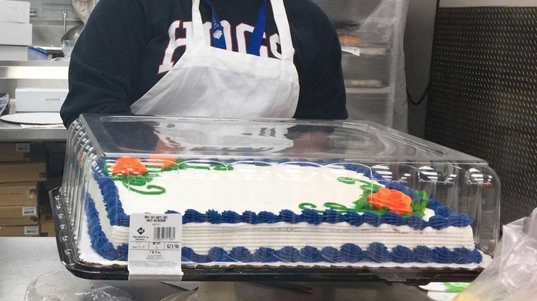 Baker holding custom sheet cake with flowers