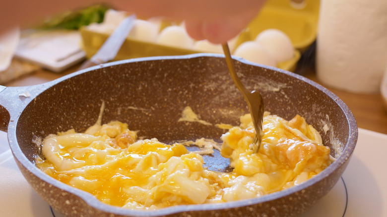 Person cooking scrambled eggs in a pan