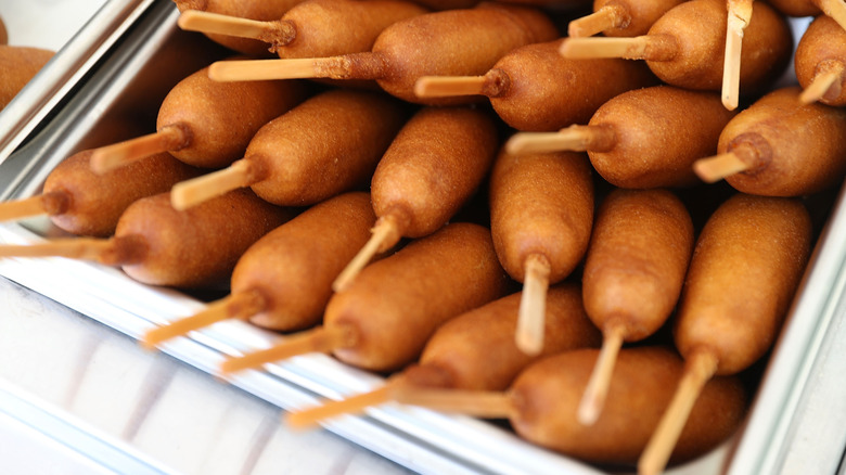Lots of corn dogs inside of a heating pan